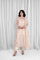 Woman wearing a beige lace outfit standing in front of white curtains