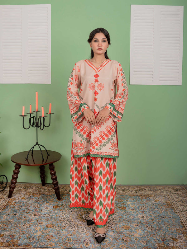 Woman in a patterned outfit standing in a room with a green wall and a small table with candles.