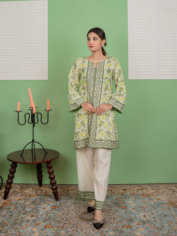 Woman wearing a green and white traditional outfit in a room with a green wall and a small table with candles.