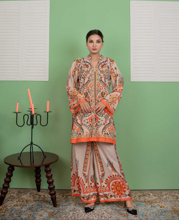 Woman wearing a traditional outfit with orange and beige patterns against a green wall.