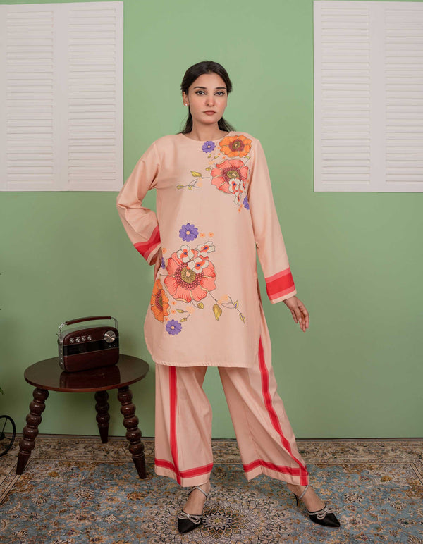 Woman wearing a peach embroidered outfit against a green wall.